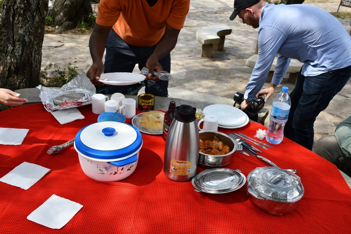       Outdoor dining setup with a variety of dishes on a red tablecloth.
  
