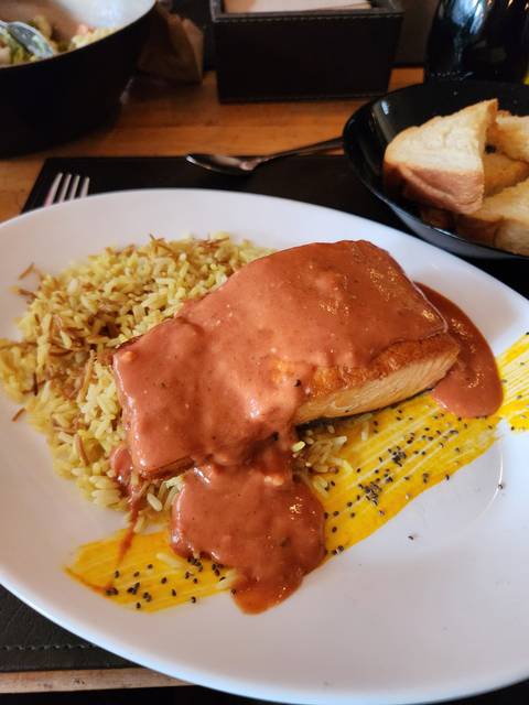 Plate of grilled chicken with rice and sauce.