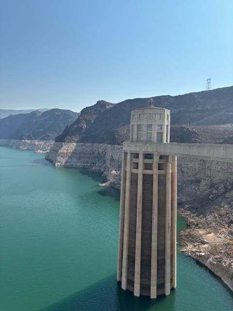 A concrete dam structure over a turquoise reservoir surrounded by rocky cliffs.