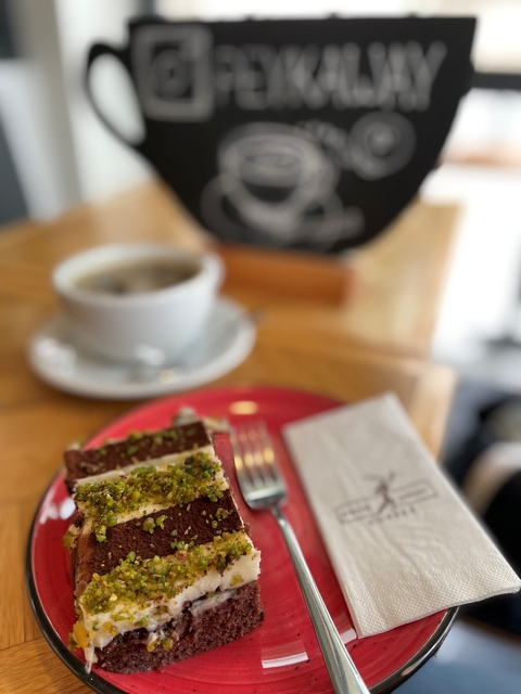       Blurry image of a cup of coffee and a dessert on a red plate.
  