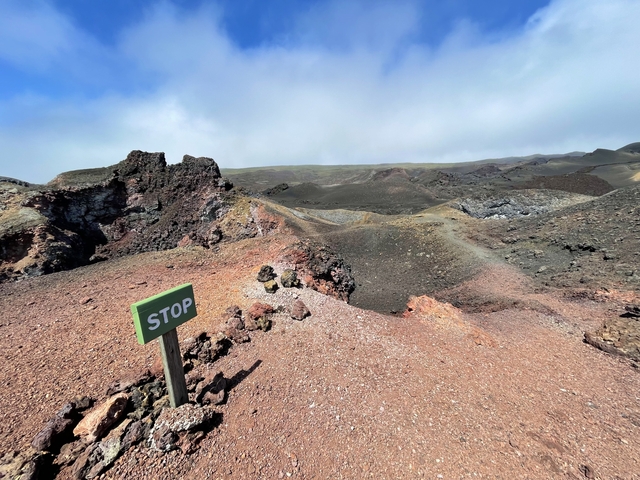       Barren volcanic landscape with a 'STOP' sign.
  