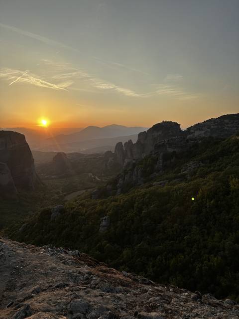       Sunset over mountains with a view of rock formations.
  