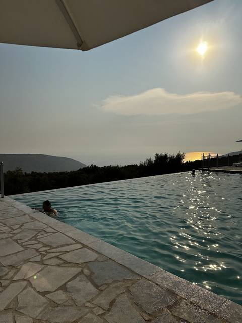       View of an infinity pool with someone swimming at sunset.
  