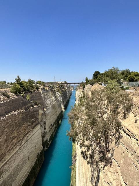       Canal with turquoise water and a bridge, surrounded by rocky cliffs.
  
