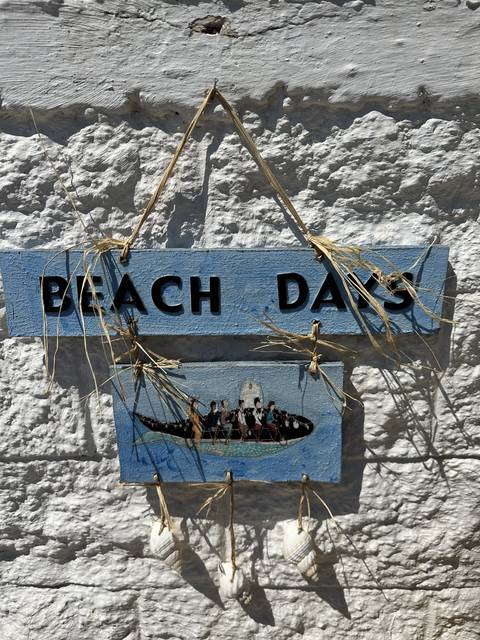       Decorative sign against a stone wall featuring a beach theme.
  