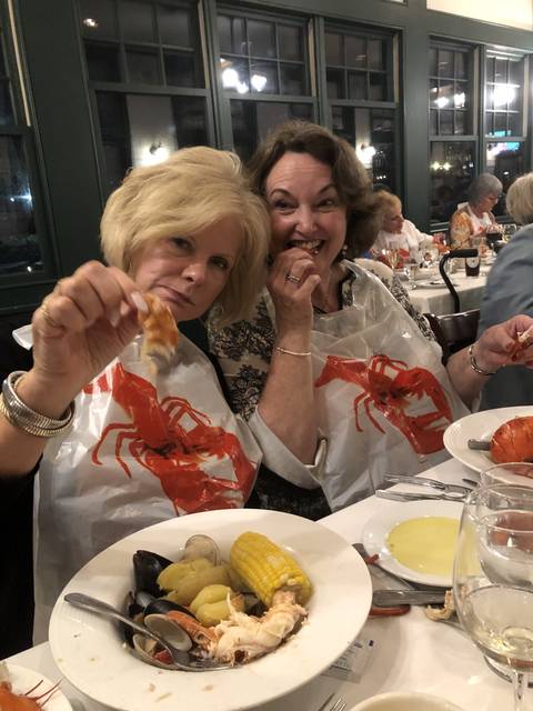 Two women dining with seafood and corn.