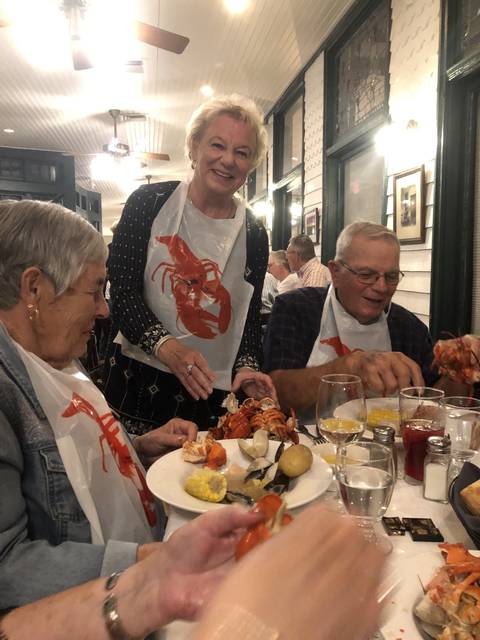 Group of people enjoying a seafood meal with lobsters and corn.