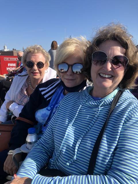 Group of women smiling and sitting outdoors on a sunny day.