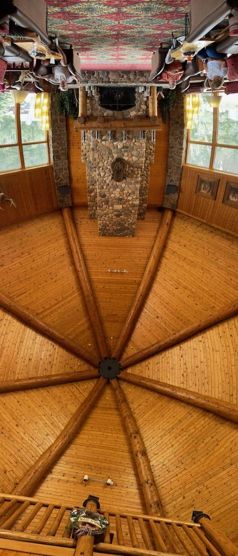       Ceiling of a lodge with wooden beams and stone fireplace.
  
