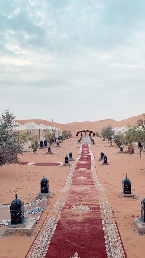 Desert camp with pathways and tents surrounded by dunes.