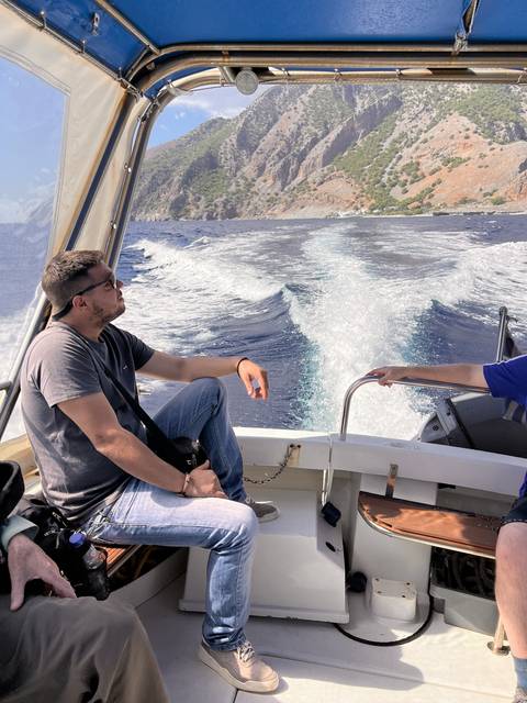 Person on a boat enjoying the view of the sea and coastline.