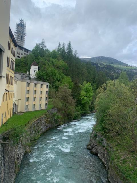 River flowing beside a wooded area and buildings in view.