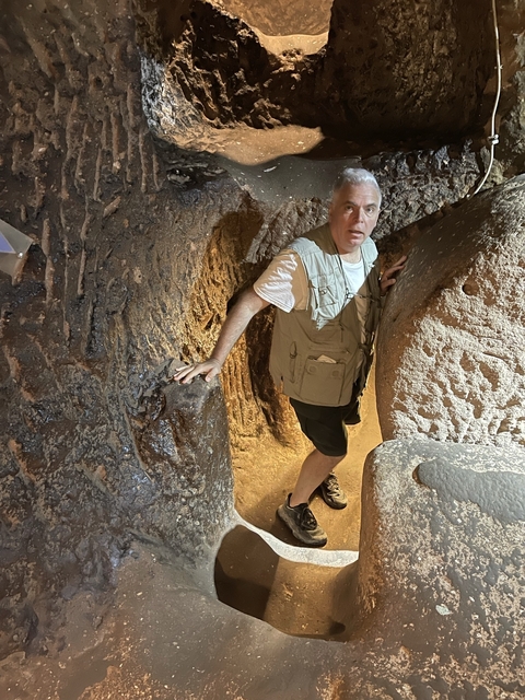       Man exploring a narrow passage within a rocky structure.
  