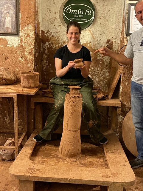       A person engaged in pottery making, creating a clay pot.
  