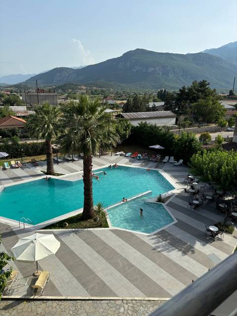 People swimming in a pool with mountain backdrop.