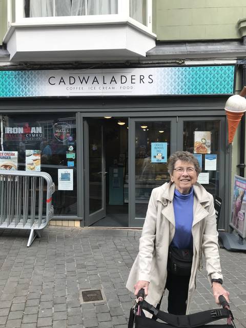       A woman standing outside a cafe entrance.
  