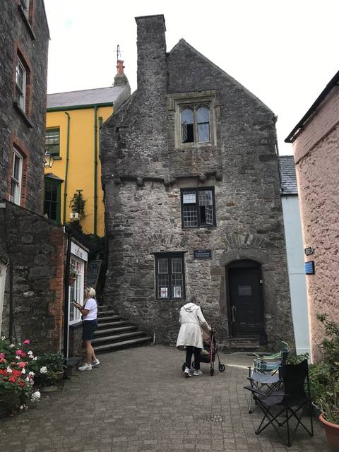 Old stone building with people walking by.