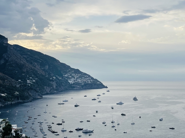       Scenic coastal view with boats on the water and hills.
  