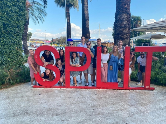       Group photo around a large Split sign.
  