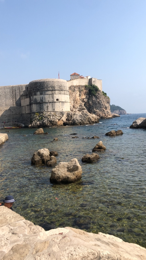      Fortress walls by the sea with rocky shoreline.
  