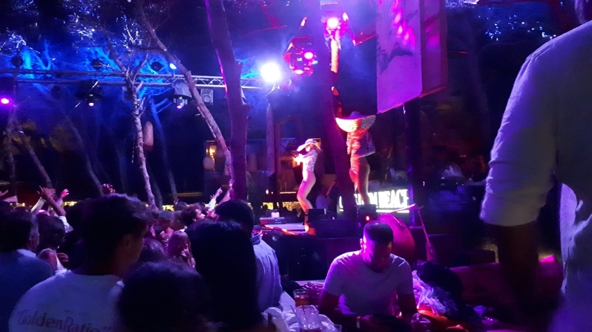       People enjoying a vibrant nightlife scene on a lit stage with performers.
  