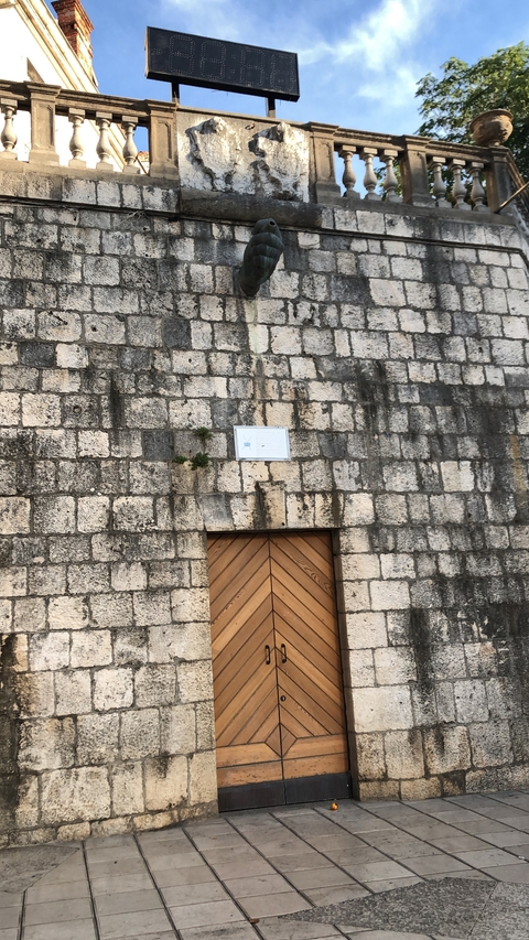       Stone wall with a door and a small sign.
  