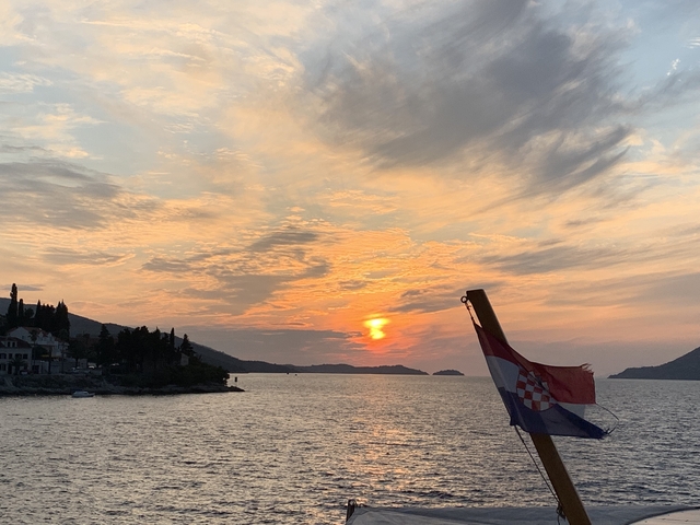       Sunset over the sea with a Croatian flag on a boat.
  