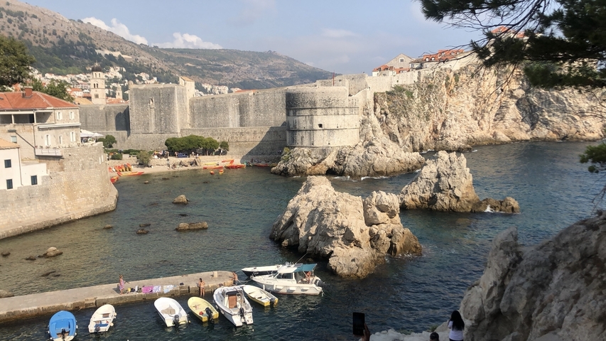       Fortified city walls next to the sea with nearby buildings.
  