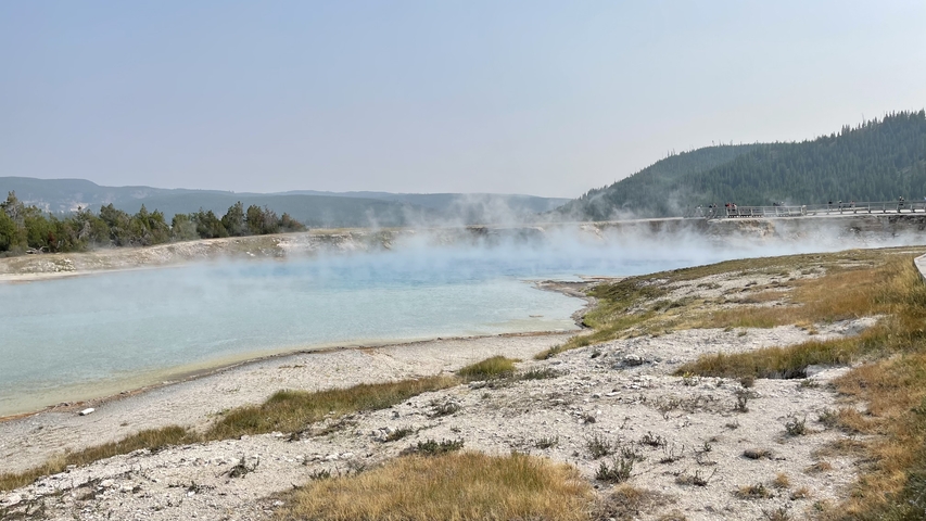 Scenic view of a geothermal feature with steam rising.