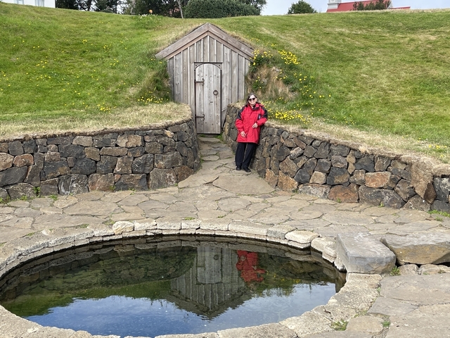 Person in red jacket standing by a stone pool.