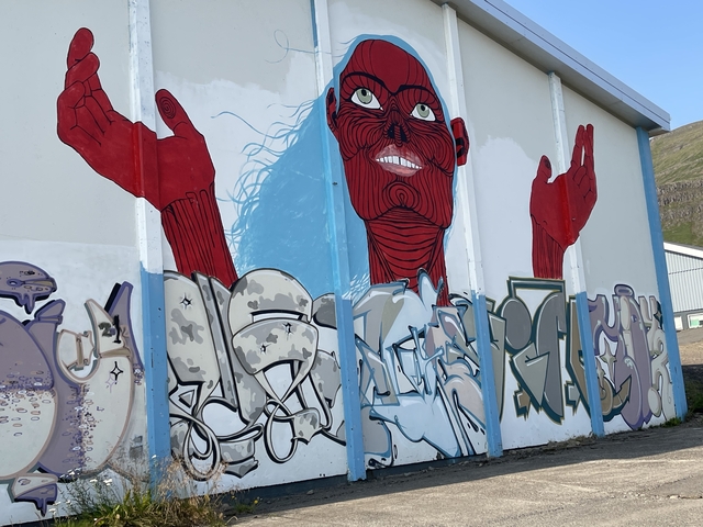       Building mural with a red figure raising hands.
  