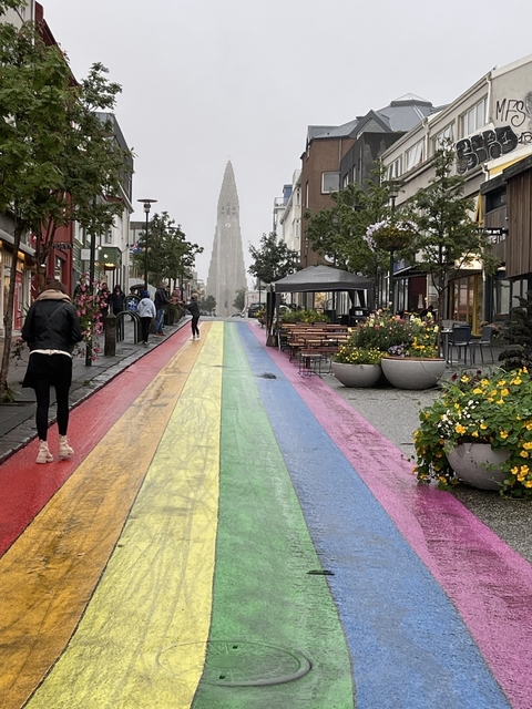Rainbow-painted street in a city with people walking.