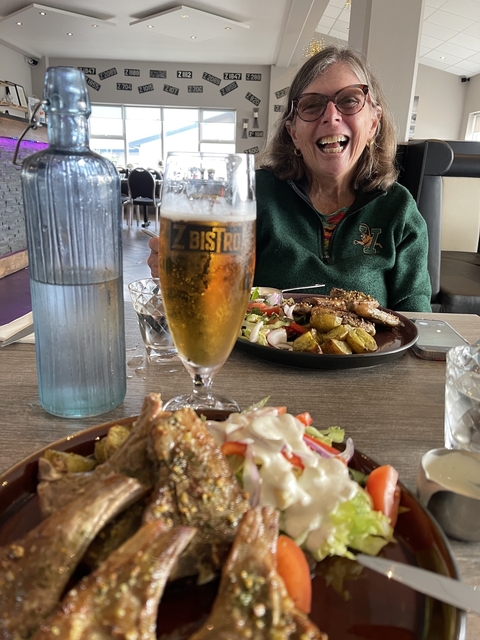 Plate of food and a glass of beer on a table.