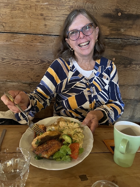       Person holding a plate of food at a rustic table.
  