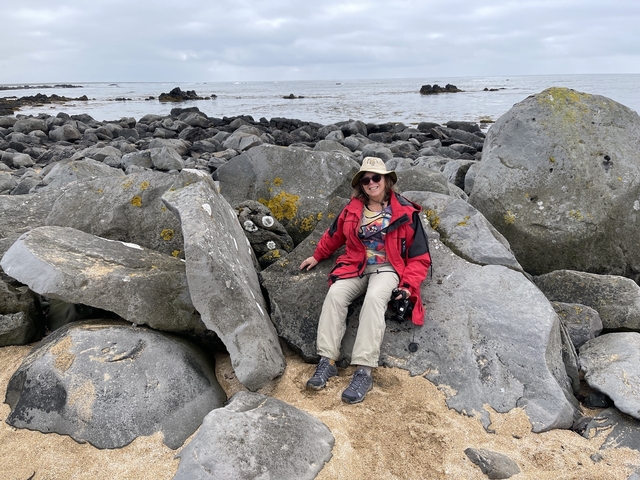 Person sitting on rocks by the coast.