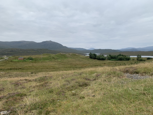 Rolling green hills with distant mountains and small lakes.