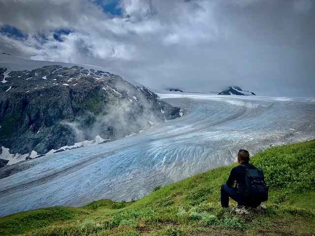       Person sitting with a view of a glacier.
  