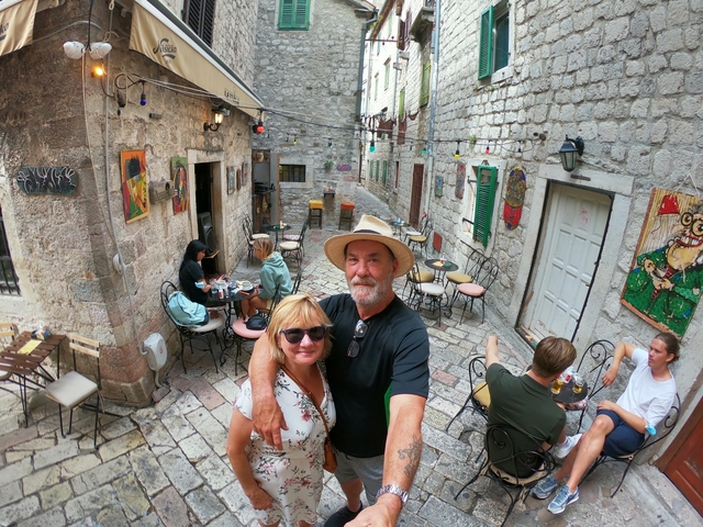 Couple taking a selfie in a quaint street cafe.