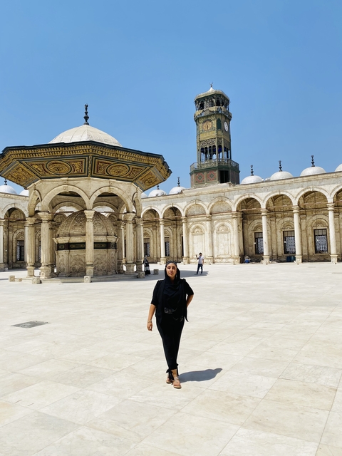       Person standing in an ornate courtyard likely in Egypt.
  