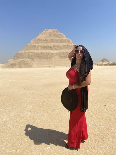       Person in red dress with ancient pyramid in Egypt.
  