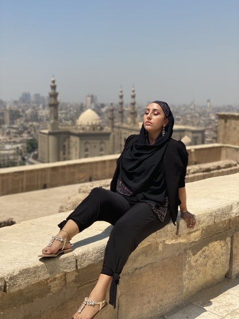       Person posing with cityscape and ancient mosque in the background.
  