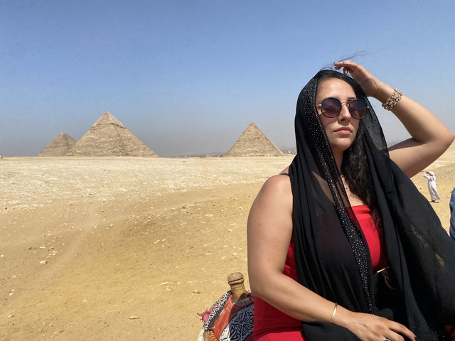       Person posing with pyramids in Egypt.
  