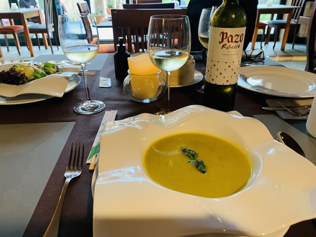 Plate of soup with asparagus garnish at a dining table.