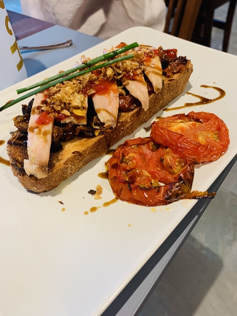 Grilled bread with toppings on a white plate.