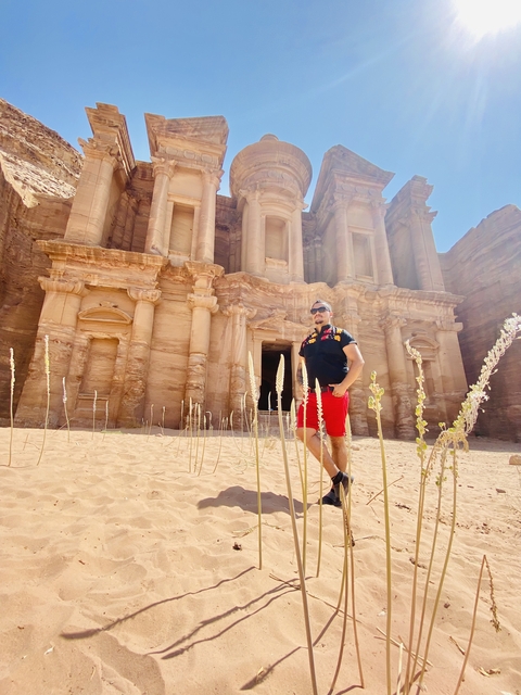       A man posing with The Monastery in Petra behind.
  