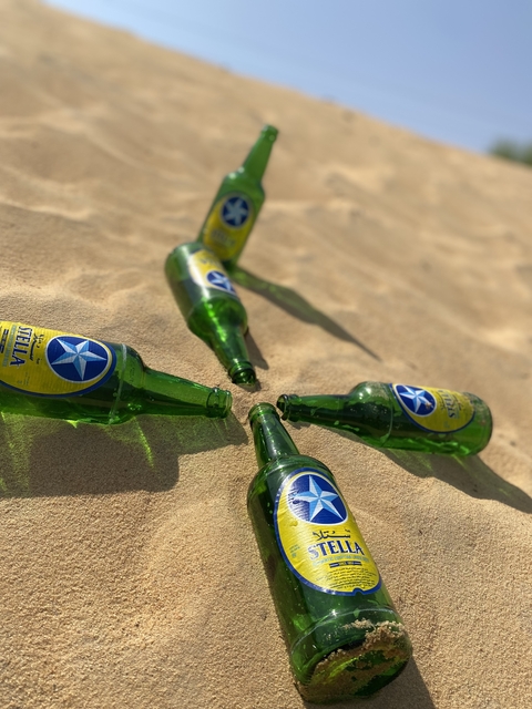       Green bottles on sandy ground.
  