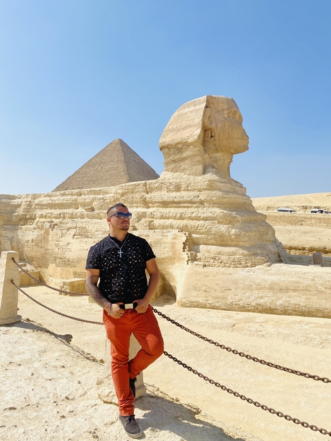       Man standing with the Sphinx and pyramid background.
  