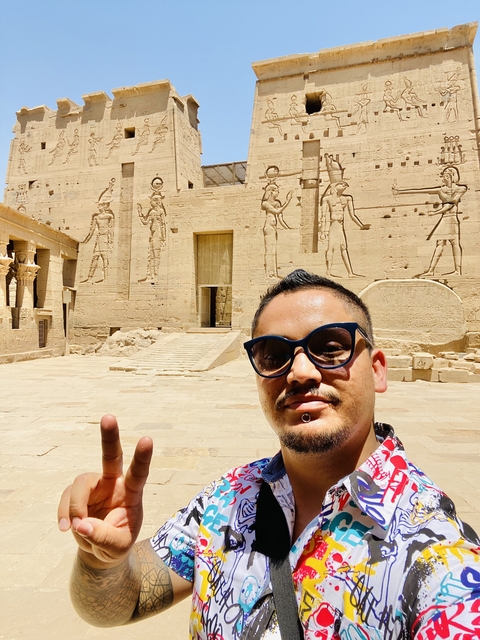       A man posing in front of ancient temple drawings.
  