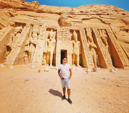       A man standing in front of the Abu Simbel temple.
  