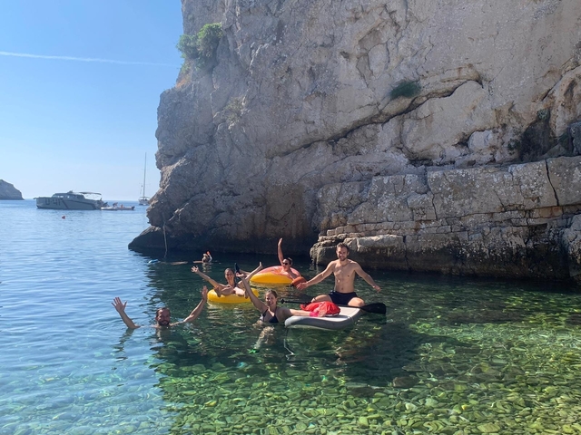 Group of people swimming and floating in a rocky cove.